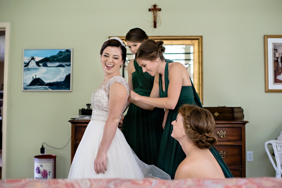 Bridesmaids help with the back of the brides wedding dress.